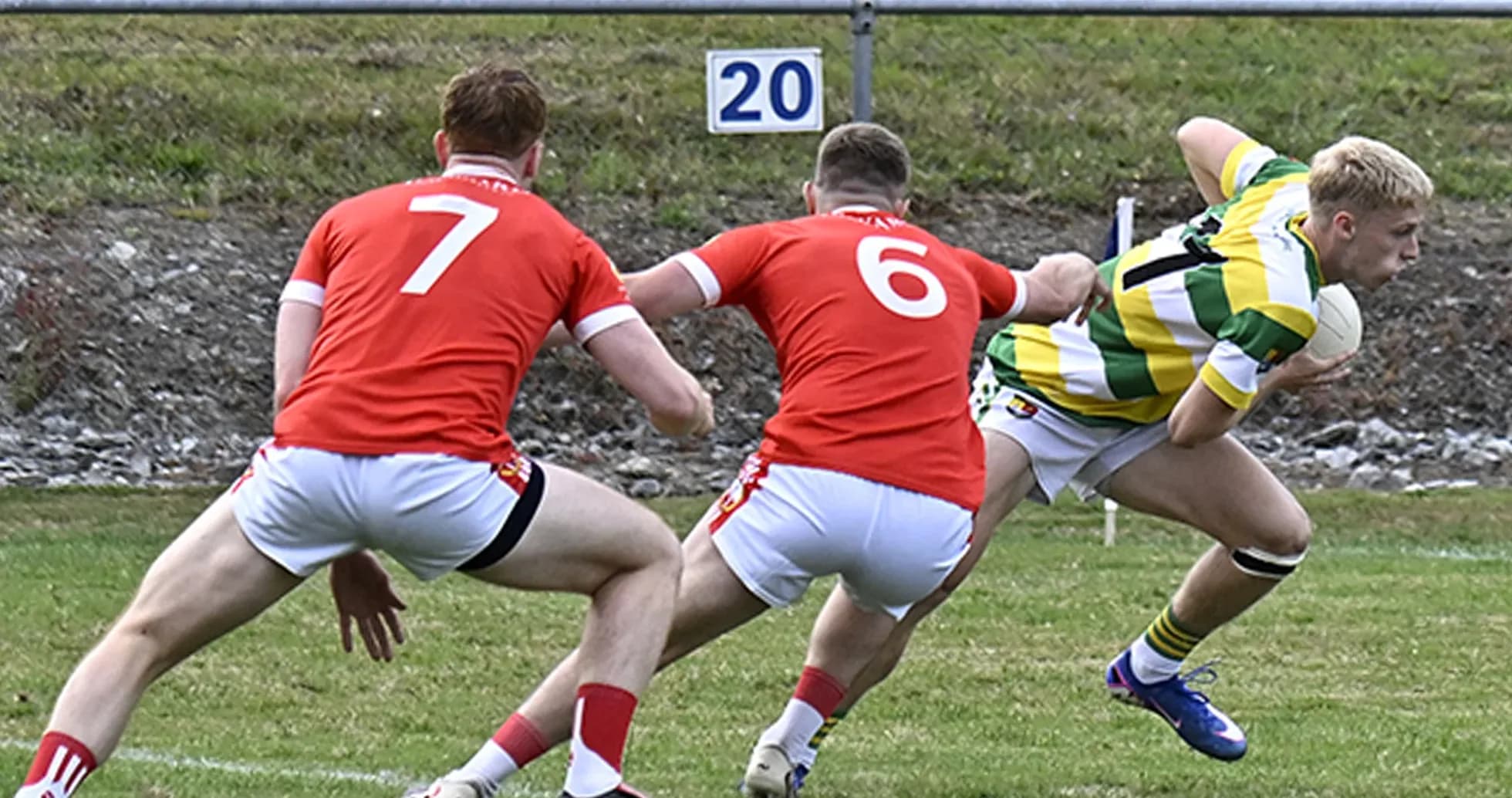 Player in green and yellow evading two defenders