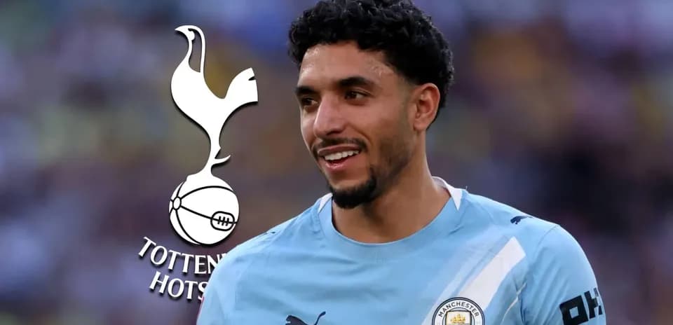 Player smiling in Manchester City kit with Tottenham logo