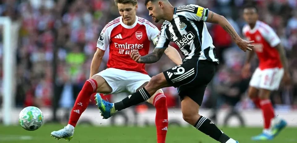 Newcastle player kicking the ball against Arsenal opponent