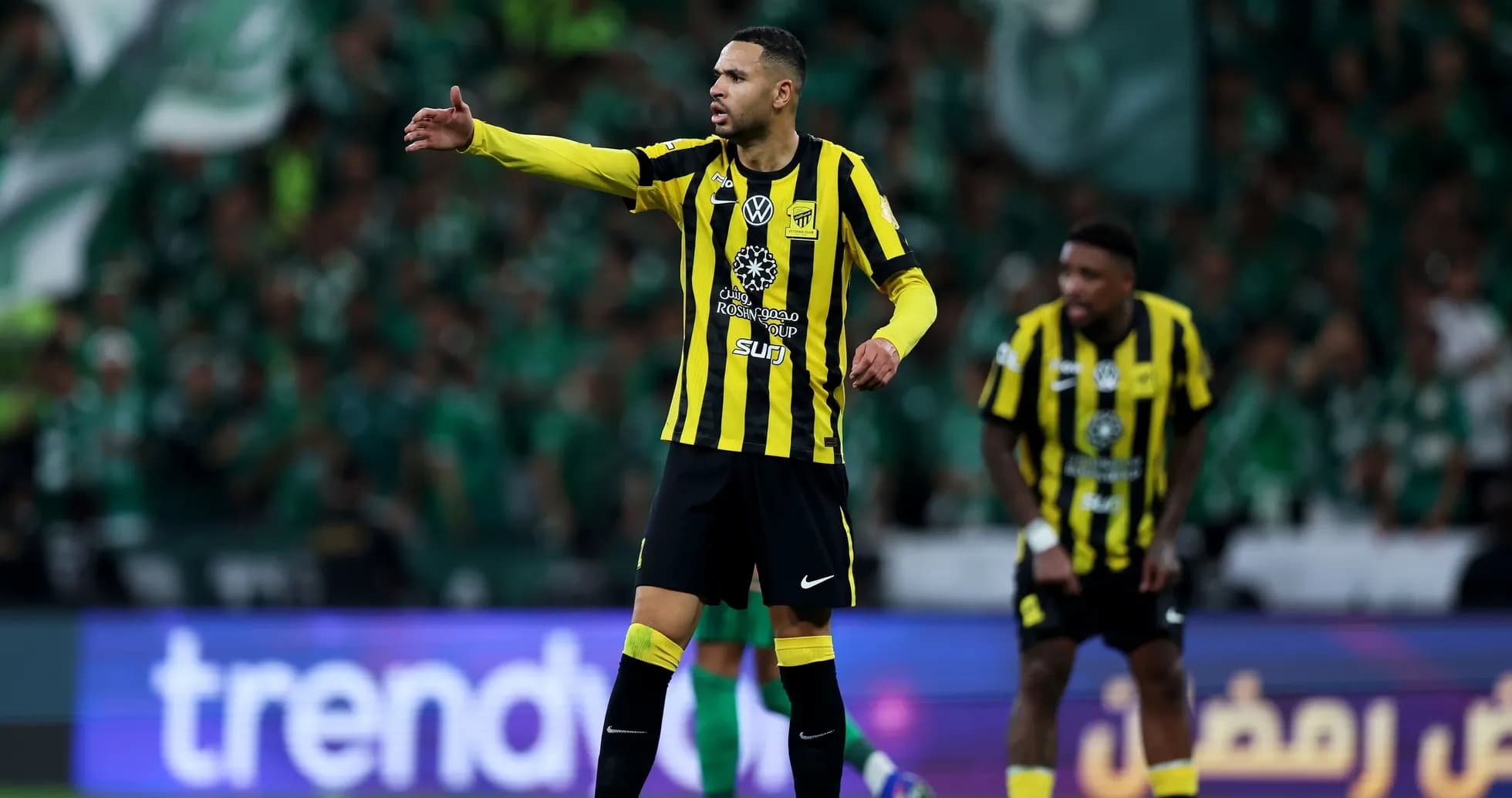 Player in yellow and black uniform directing teammates on field