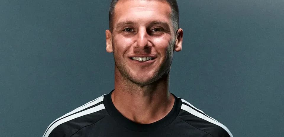 Athlete in black jersey smiling against gray background