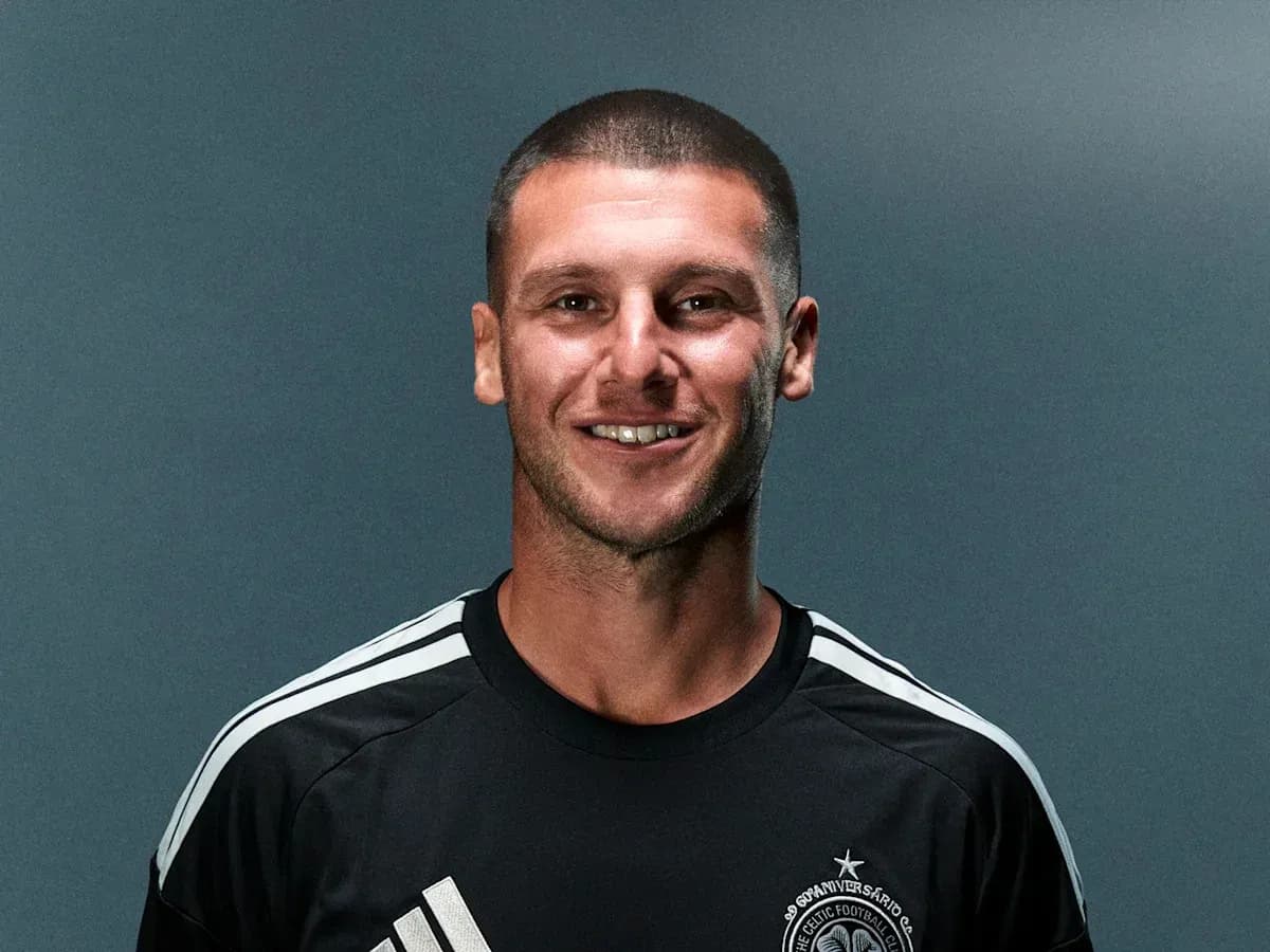 Athlete in black jersey smiling against gray background