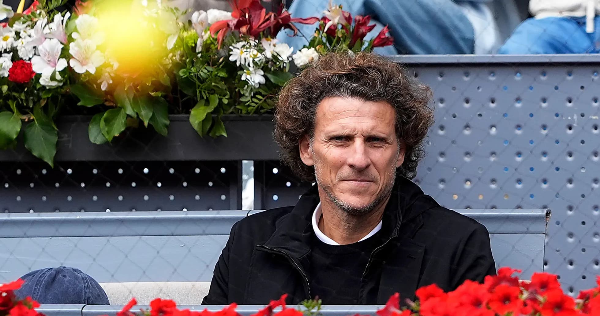 Man seated in stands with flowers in background