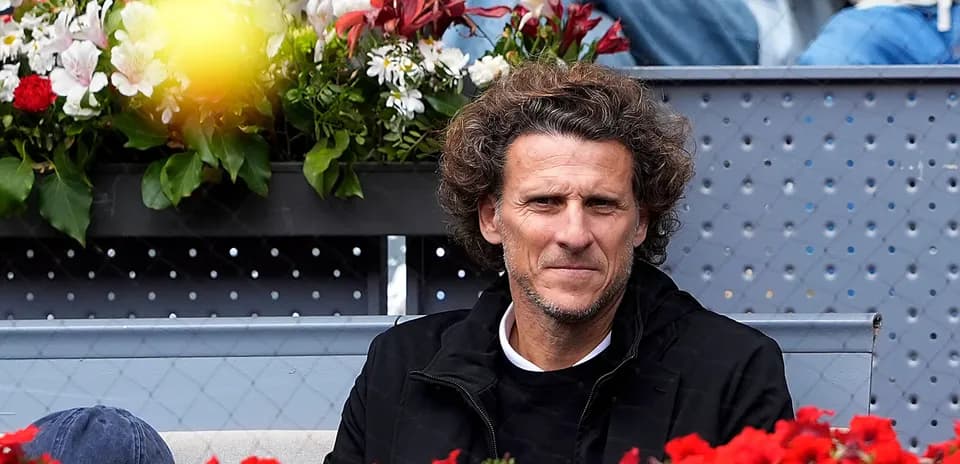 Man seated in stands with flowers in background