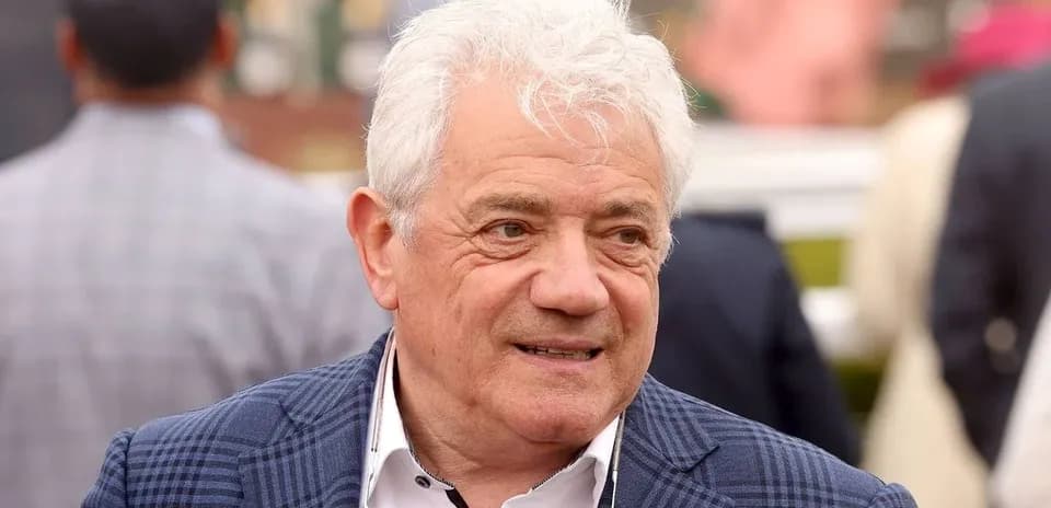 Man with white hair wearing a blue checkered jacket