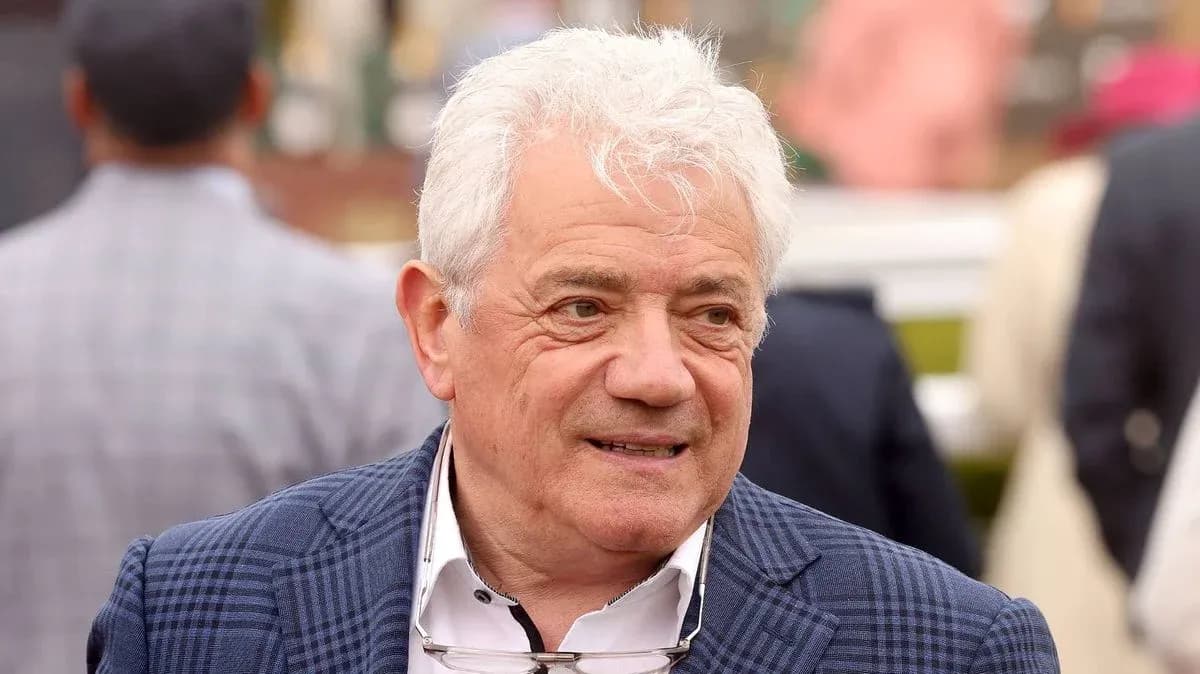 Man with white hair wearing a blue checkered jacket