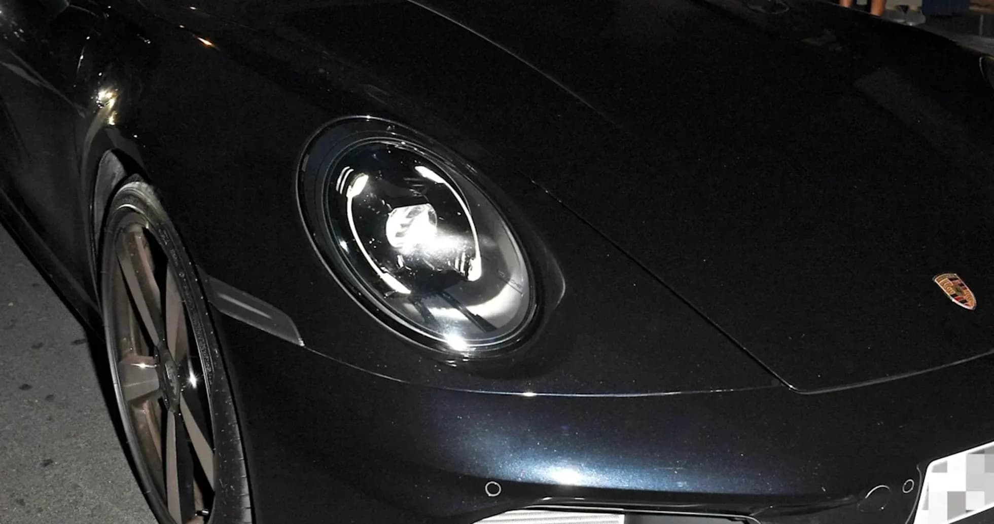 Two men in a black Porsche car at night