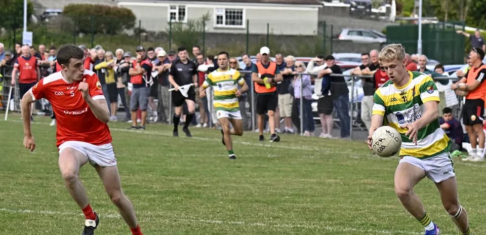 Player in green and yellow jersey with ball, pursued