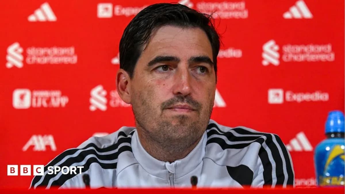 Manager speaking at press conference with team logo backdrop