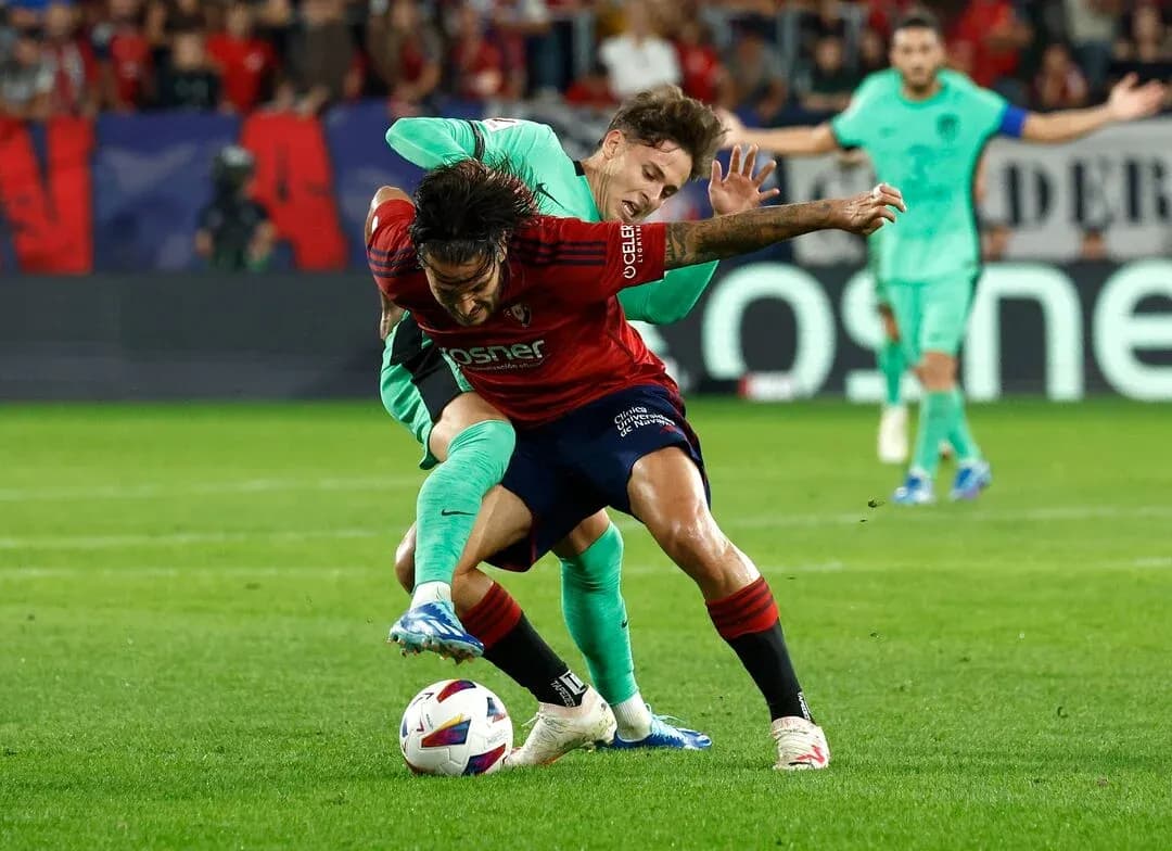 Osasuna player challenged by Atletico Madrid player