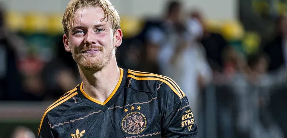 Player smiling in Ajax black and orange jersey