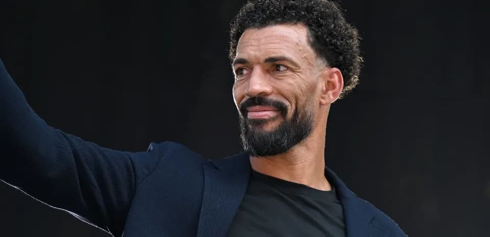 Man in a blazer waving to the crowd