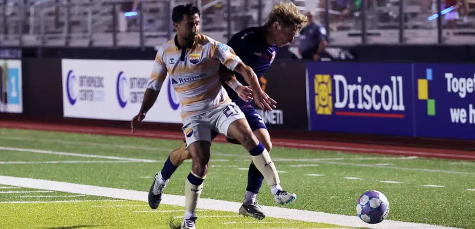 Player tackling opponent during USL League One match