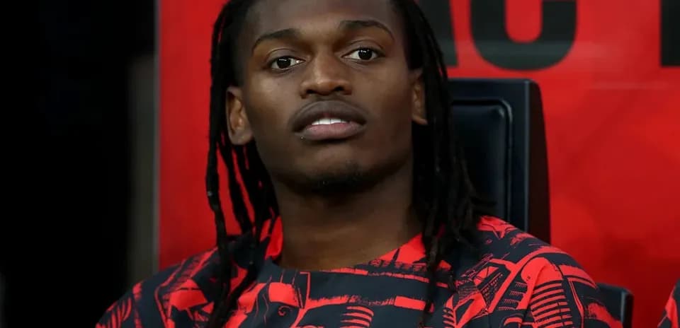 Player seated on bench wearing AC Milan kit