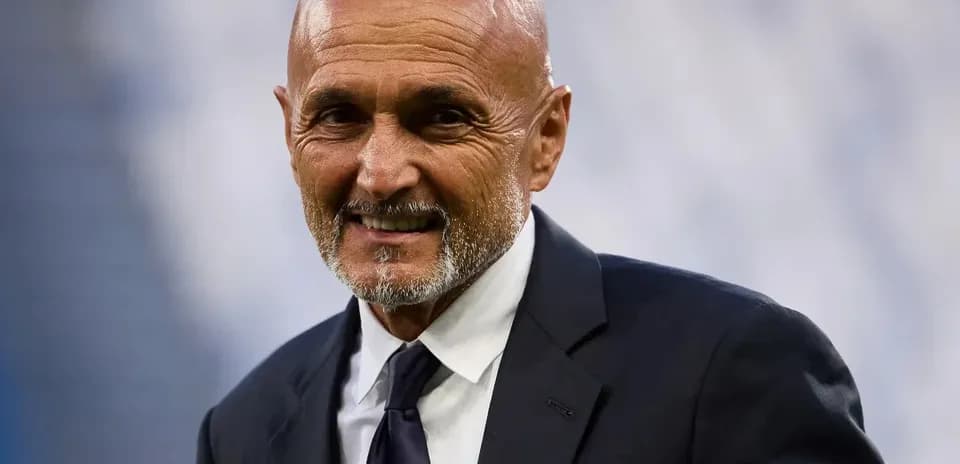Coach smiling while wearing a suit on the field