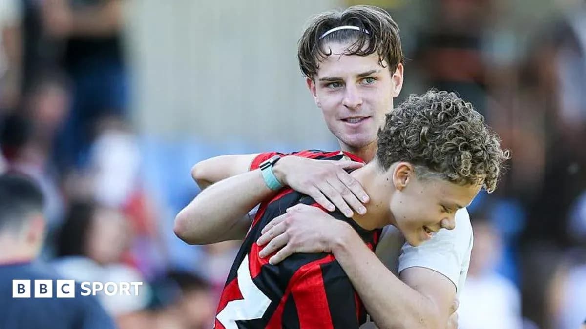Two players embracing on the pitch after match