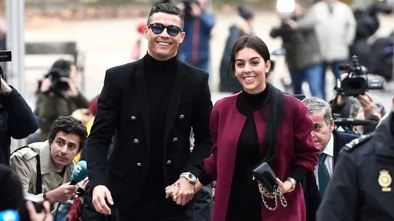 Couple walking hand in hand, surrounded by photographers