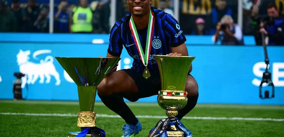 Player celebrating with two trophies on field