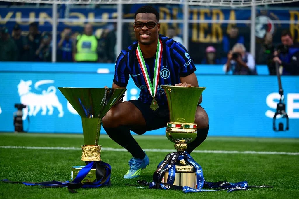 Player celebrating with two trophies on field