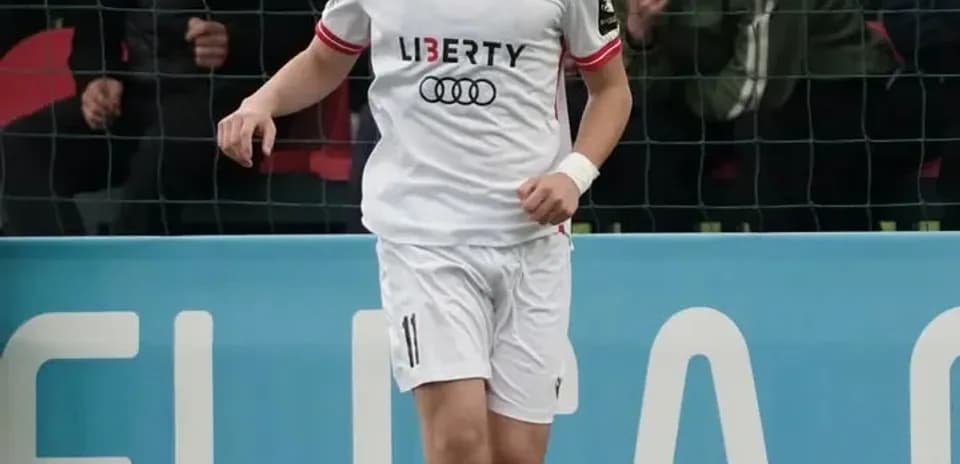 Player in white kit dribbling the ball on field