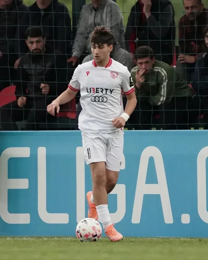 Player in white kit dribbling the ball on field
