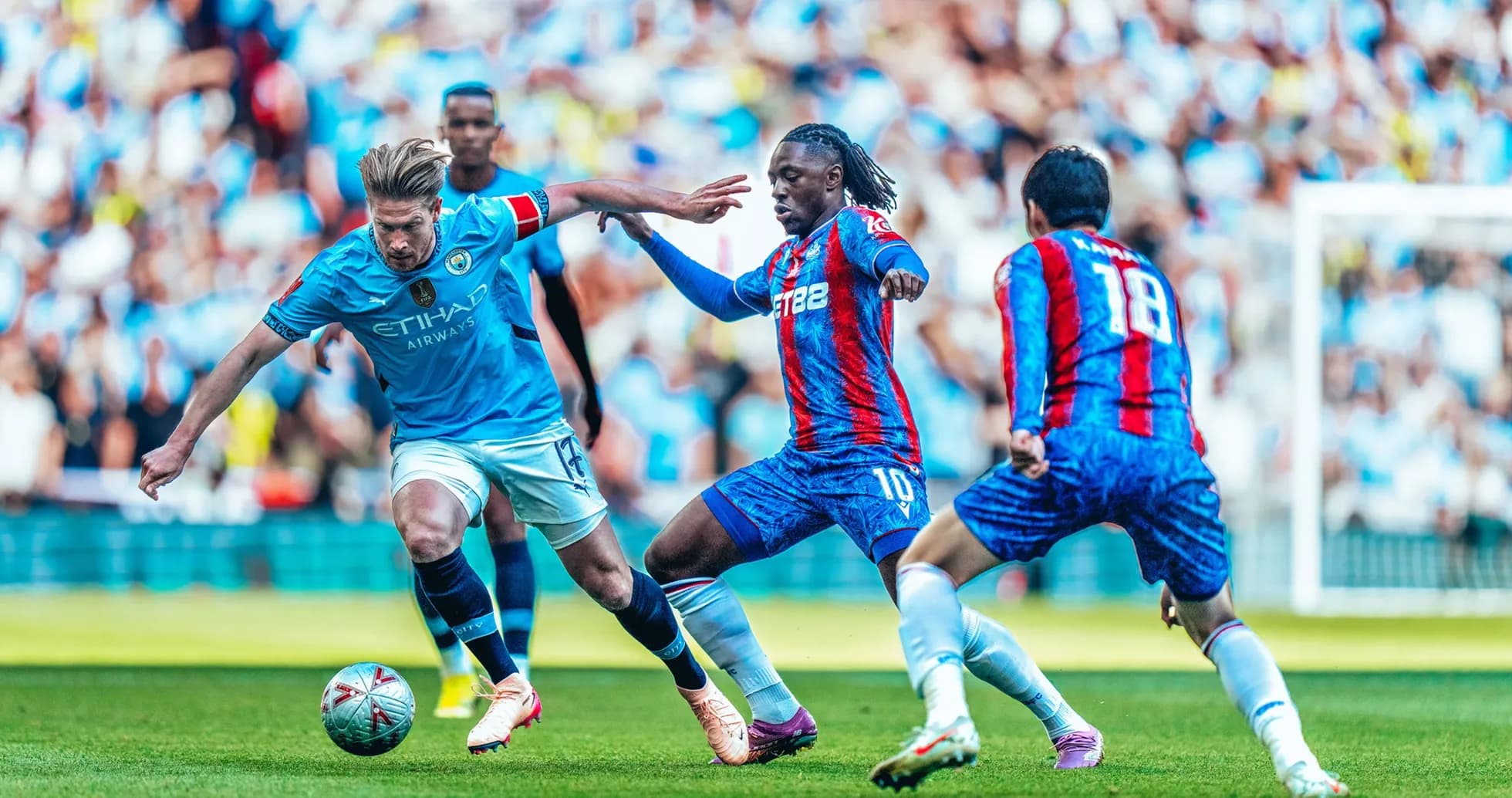 Manchester City player dribbling past Crystal Palace opponents