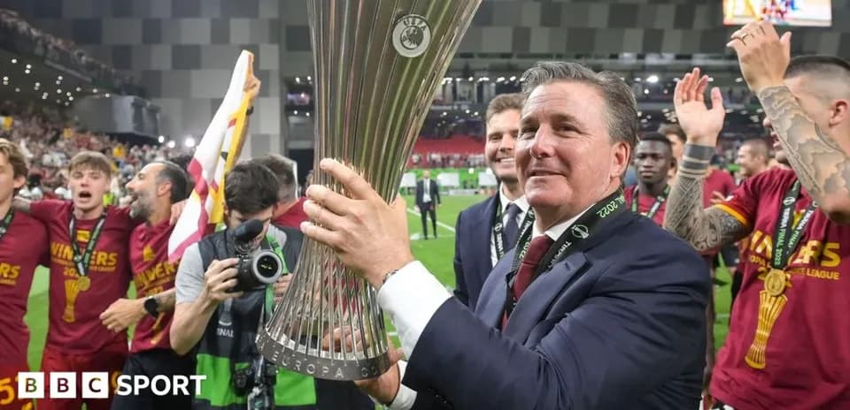 Coach celebrating with Europa League trophy and players