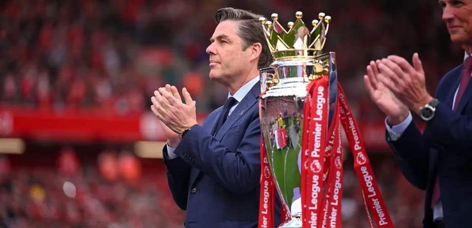 Person applauding next to Premier League trophy