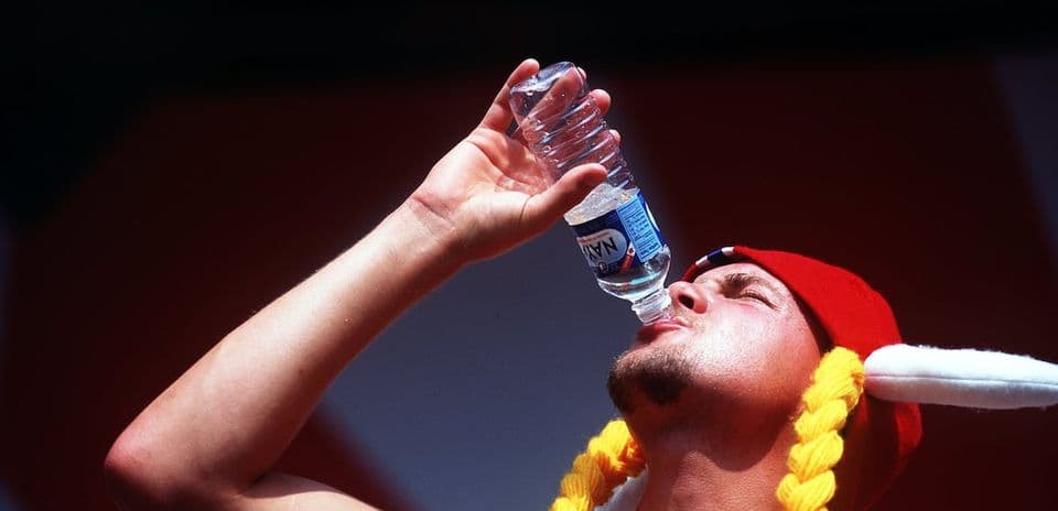 Person drinking water from a bottle in sun