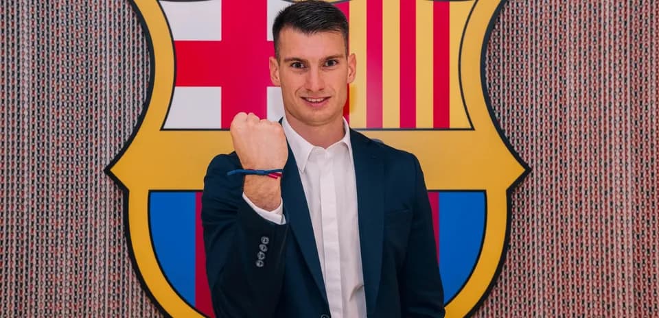 Player posing with fist raised in front of Barcelona logo