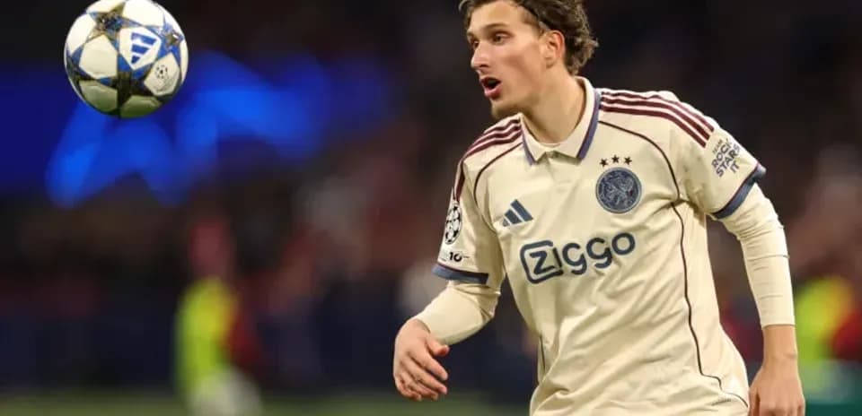 Player in Ajax kit tracking the ball during match