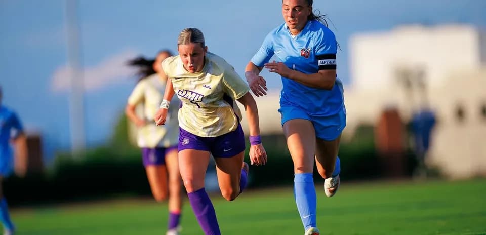 Two female soccer players racing for the ball