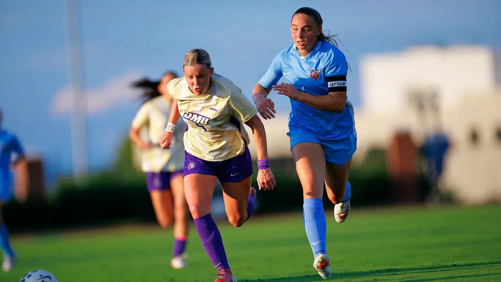Two female soccer players racing for the ball