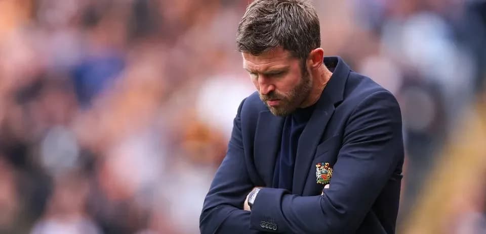 Coach looking down with arms crossed during match