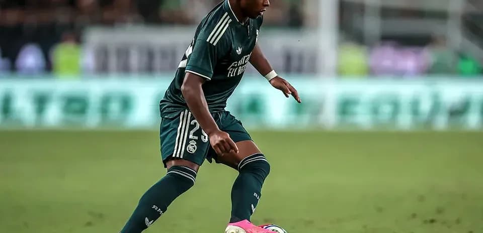 Player in green kit dribbling ball on field