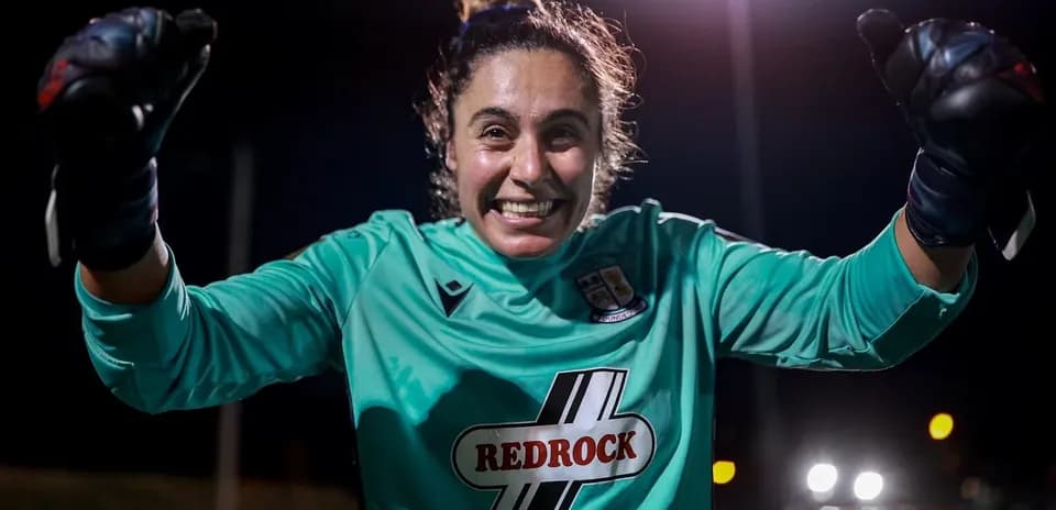 Goalkeeper celebrating with clenched fists at night