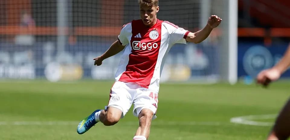 Player in Ajax kit kicking the ball on field