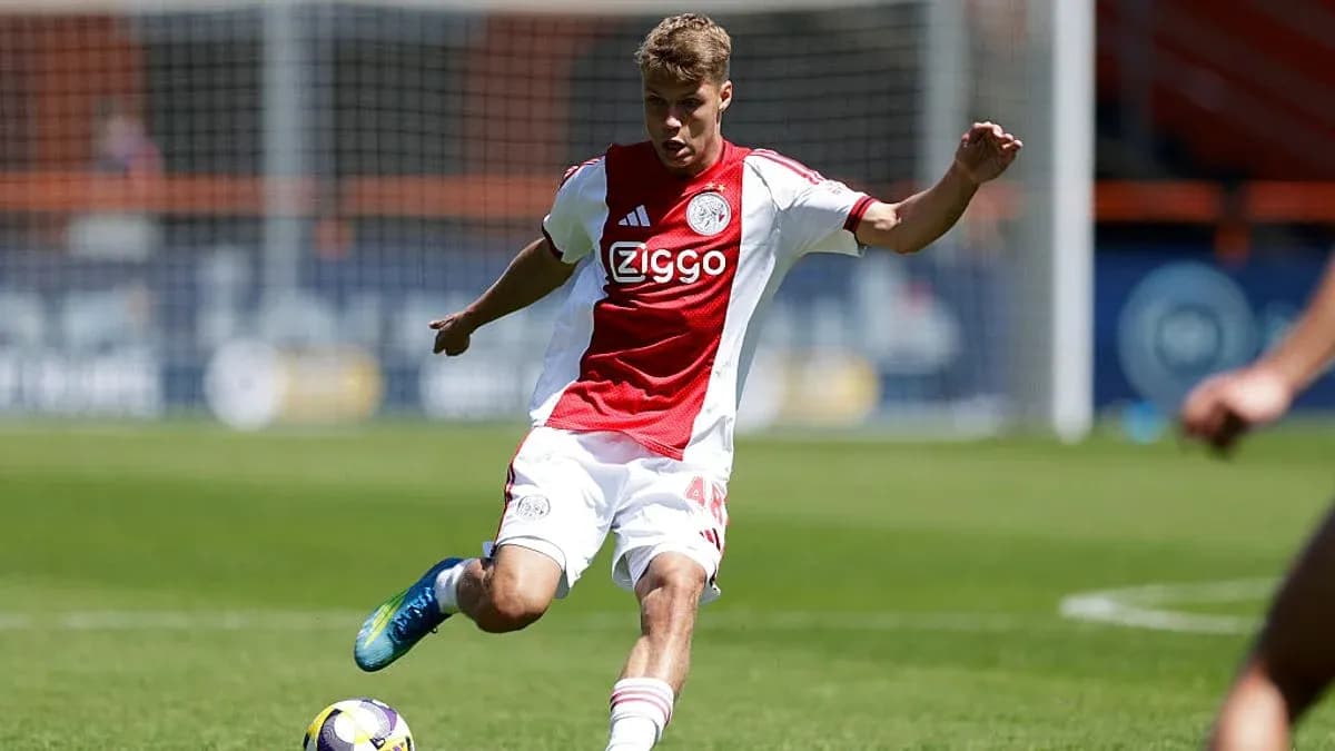 Player in Ajax kit kicking the ball on field