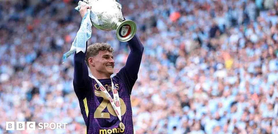 Player celebrating with trophy in stadium crowd