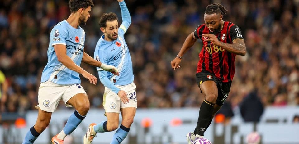 Bournemouth player dribbling past Manchester City defenders