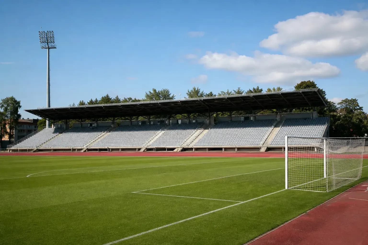 Empty football stadium with green pitch and goalpost
