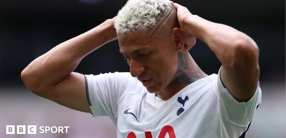 Player holding head during match, wearing Tottenham kit
