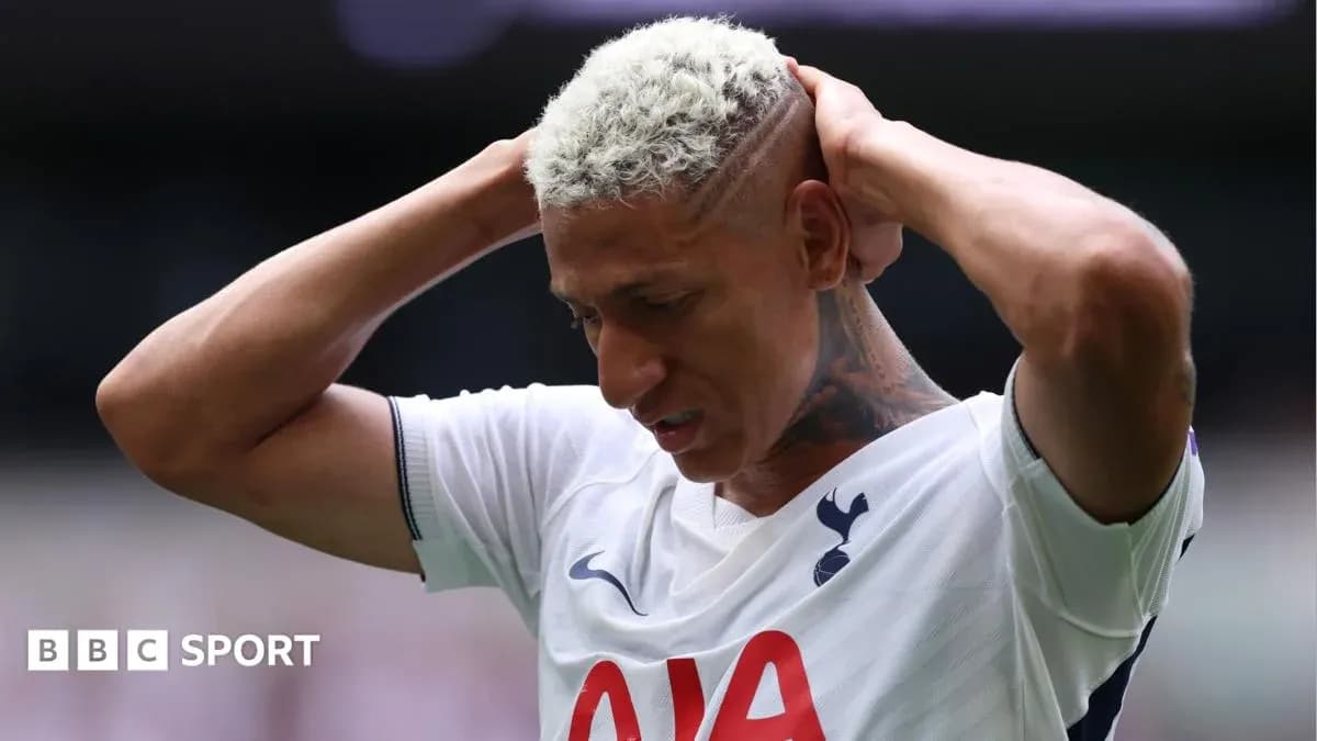 Player holding head during match, wearing Tottenham kit