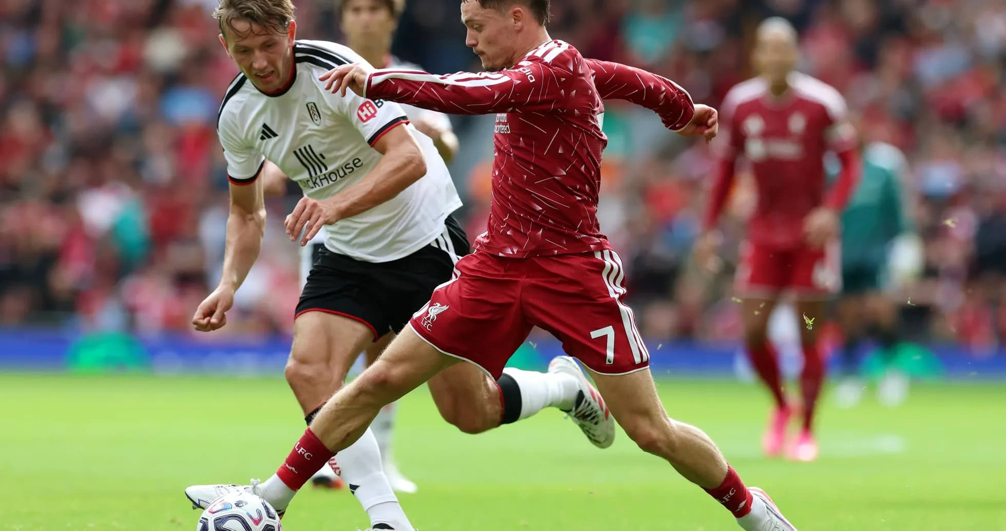 Liverpool player tackling Fulham opponent during match