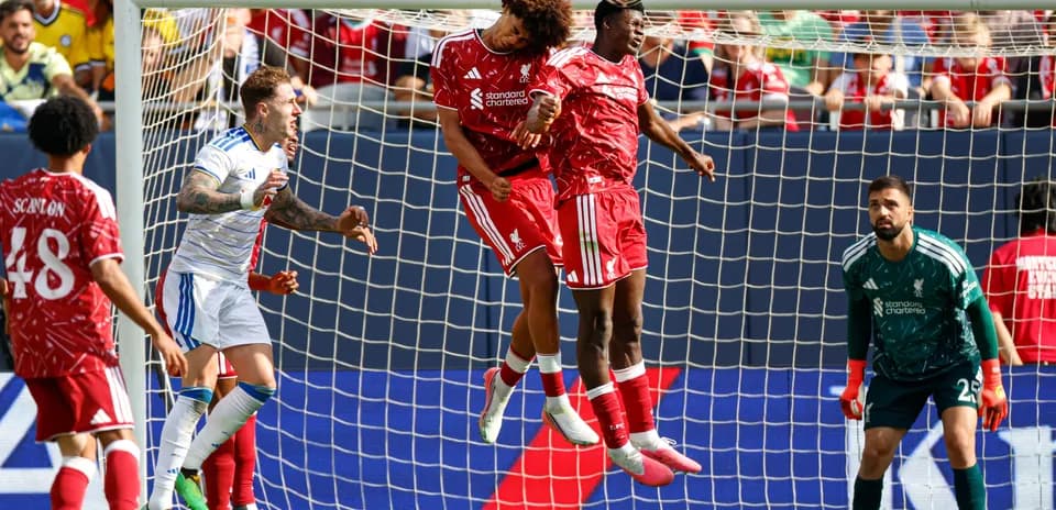Two Liverpool players jumping for a header in goal area
