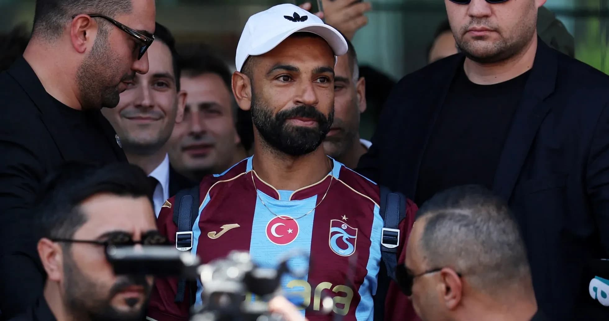 Player arriving surrounded by security personnel