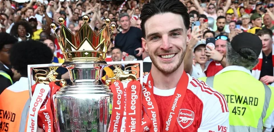 Player holding Premier League trophy with fans cheering