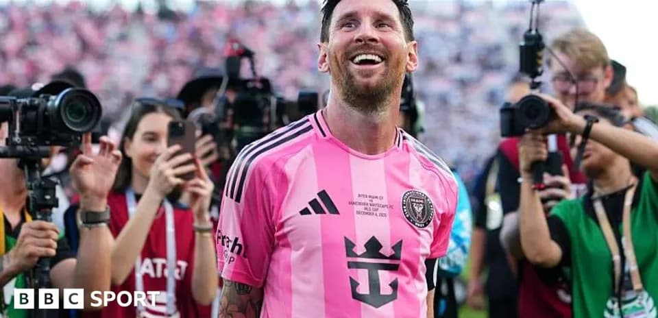 Lionel Messi smiling in pink jersey surrounded by fans