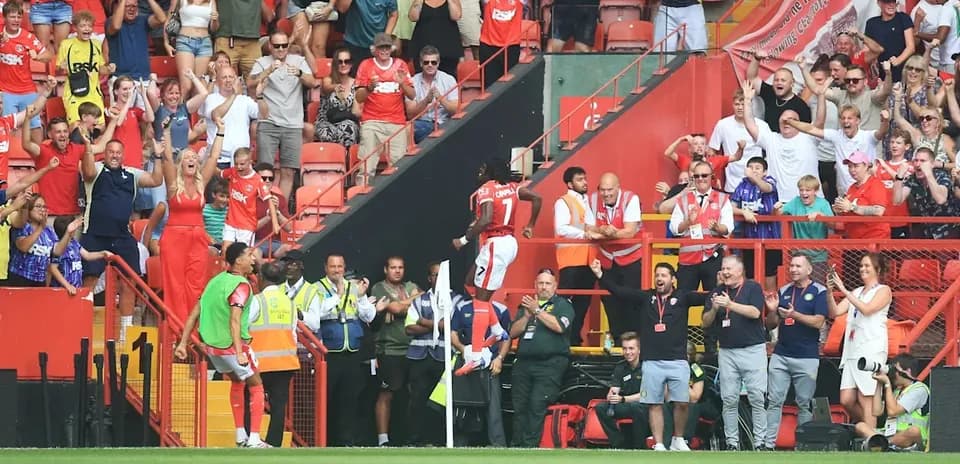 Fans celebrating as player scores goal near corner flag