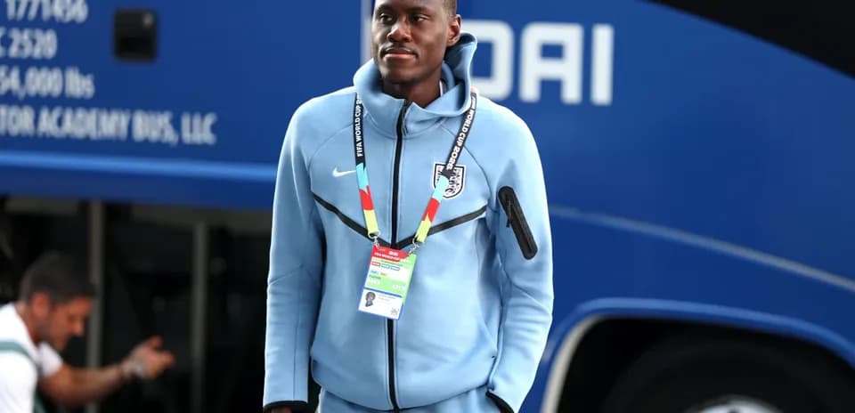 Player wearing team tracksuit near team bus